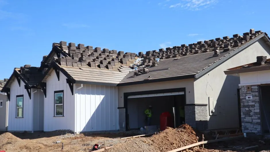 Modern house under construction with unfinished roof, showcasing architectural details.